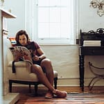 Woman enjoying a peaceful moment reading a magazine at home in a stylishly decorated room.