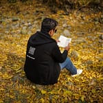 A man reading a book on fallen autumn leaves in New Theed, Kashmir.