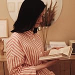 A woman enjoys a quiet moment reading a book at home, offering a serene and contemplative mood.