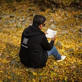 A man reading a book on fallen autumn leaves in New Theed, Kashmir.