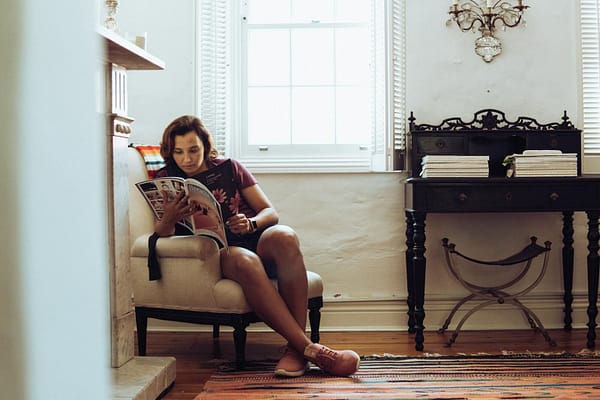 Woman enjoying a peaceful moment reading a magazine at home in a stylishly decorated room.