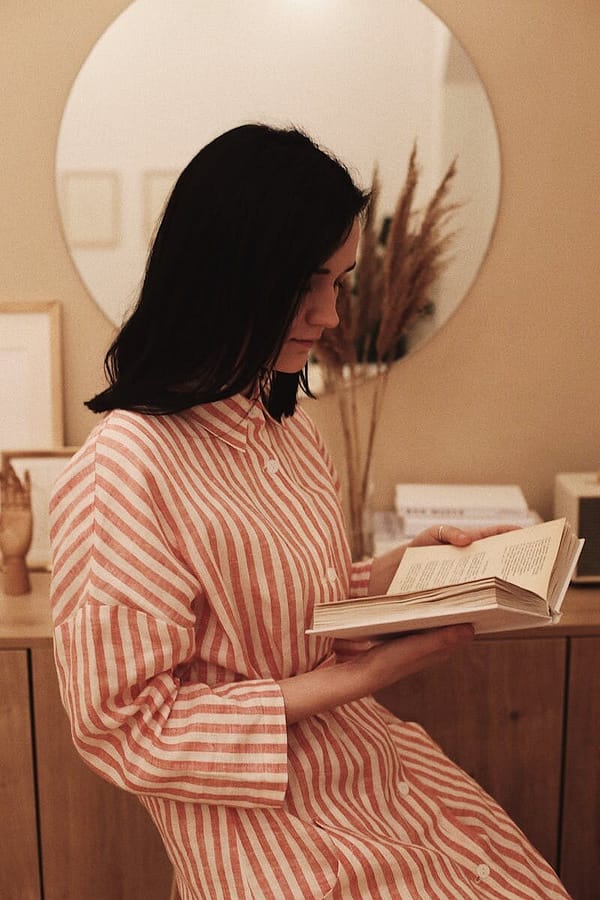 A woman enjoys a quiet moment reading a book at home, offering a serene and contemplative mood.
