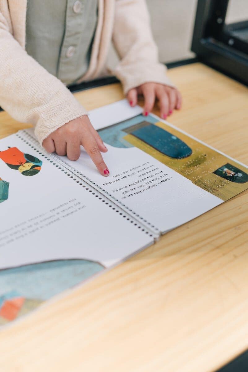 A child interacts with an illustrated book, focusing on the tactile experience of reading.